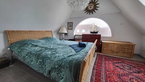 A bedroom with a bed, a lamp, a dresser, a rug, and a sun decoration on the wall. - Ville Quanel, Wissant Bay (Wissant)