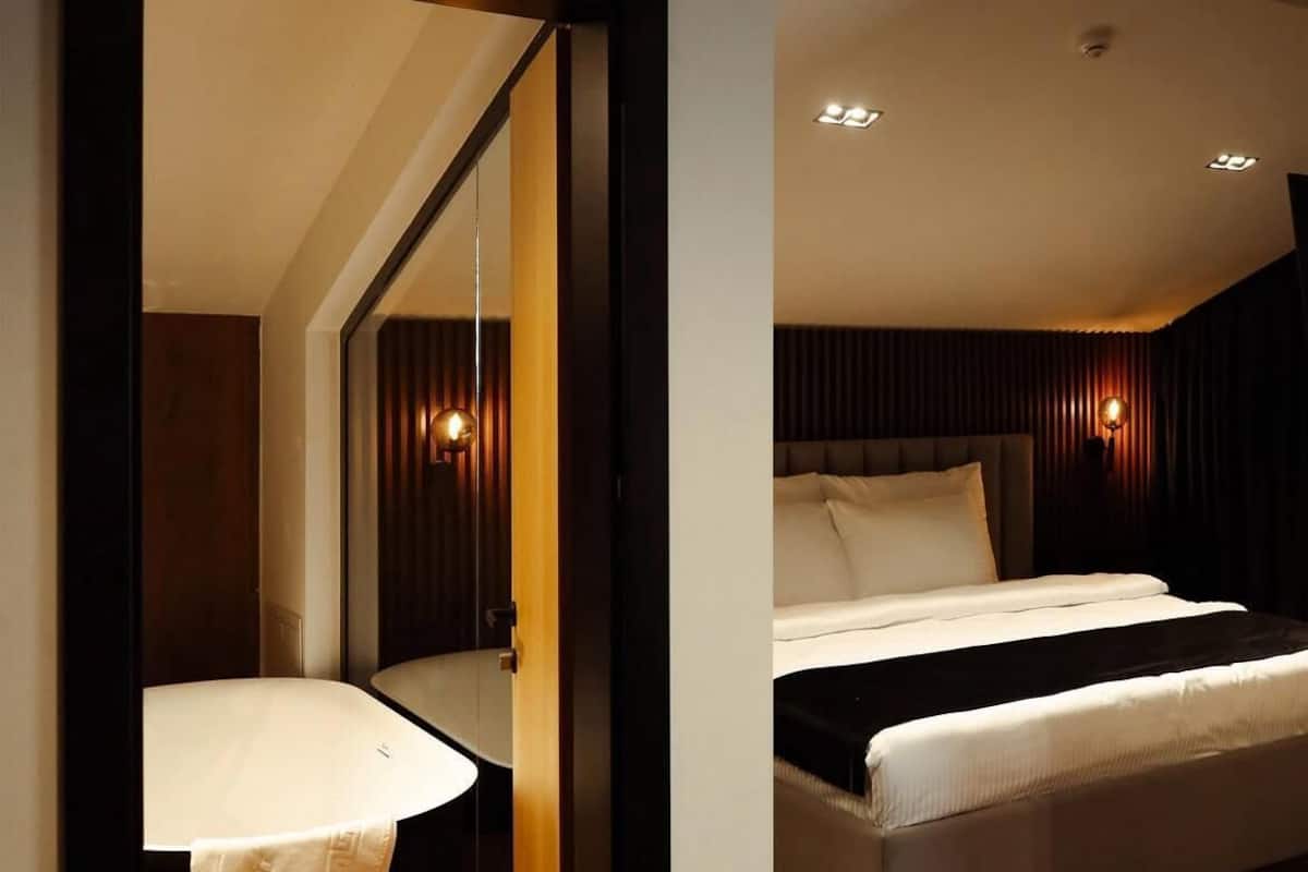 A modern bedroom with a large bed, a bedside table, and a mirror.