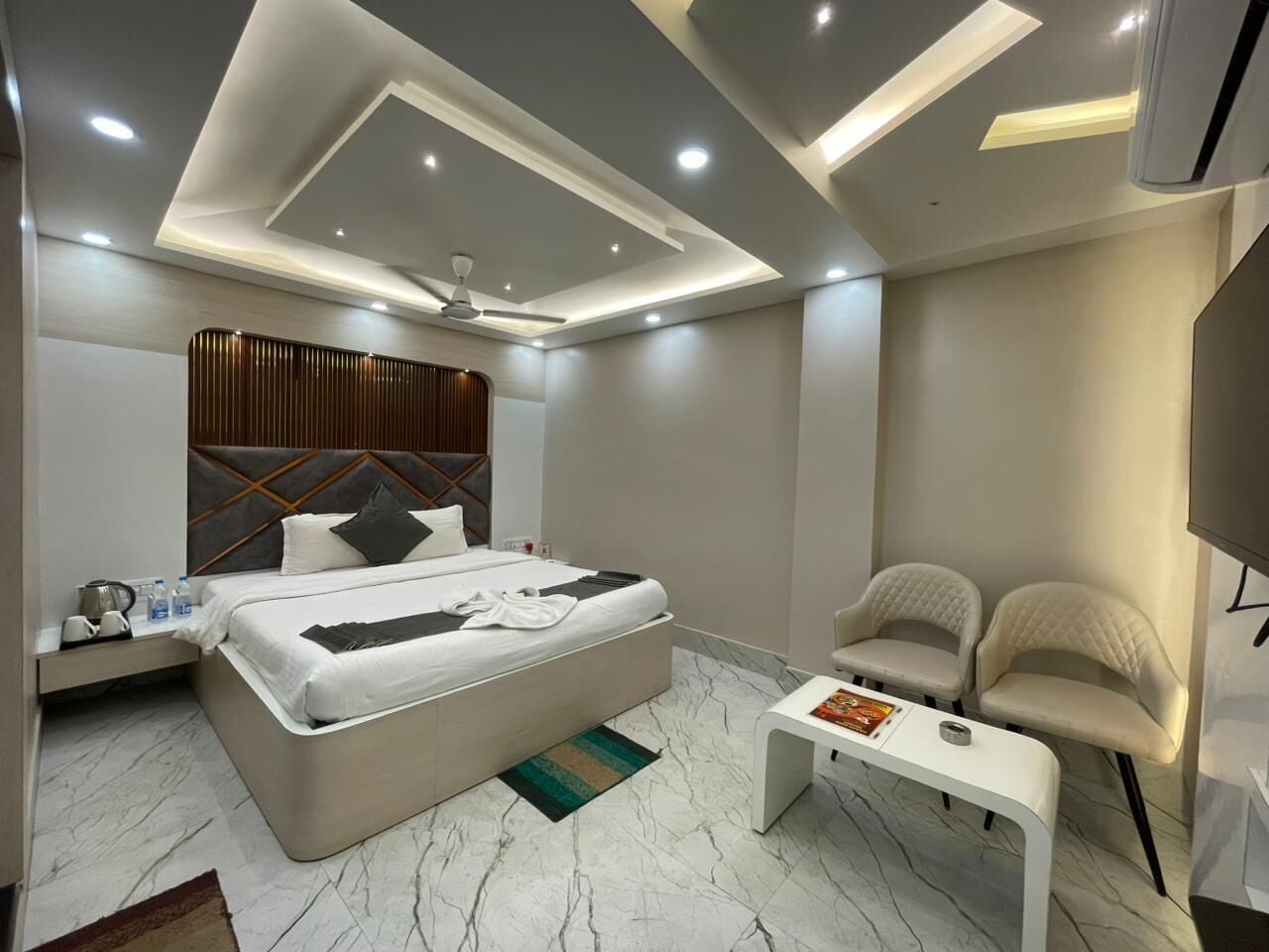 Una moderna camera d'albergo con un letto grande, due poltrone, un tavolino e una ventola a soffitto.