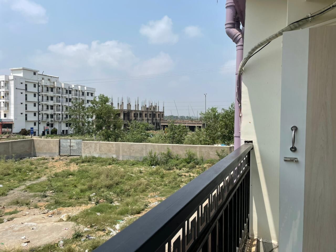 Une vue d’un immeuble doté d’un balcon, avec un mur en béton et un chantier de construction en arrière-plan.