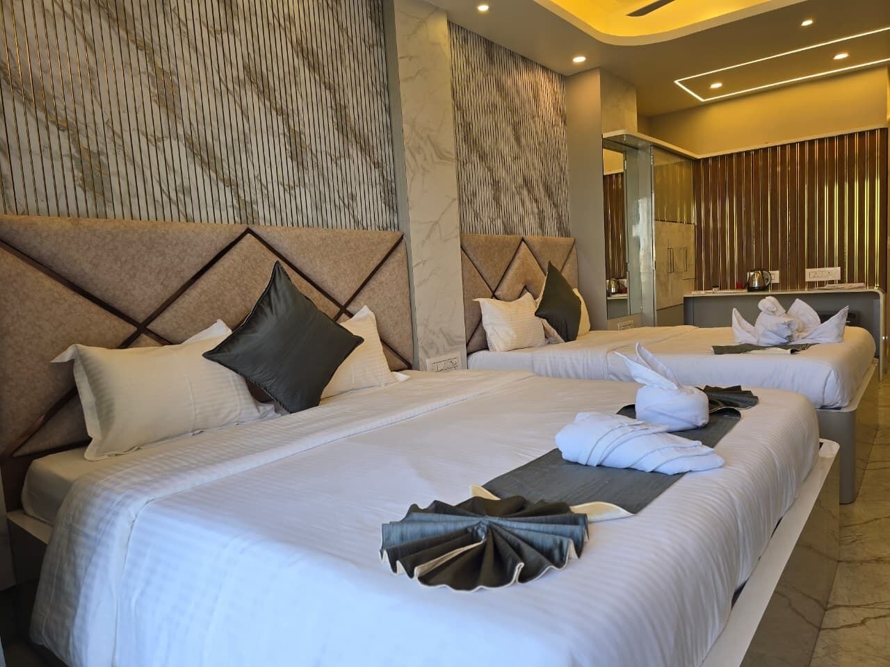 A hotel room with two beds, each with white linens and pillows, a marble-patterned wall, and a modern design.