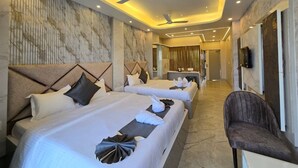 A hotel room with two beds, a sitting area, a ceiling fan, and a TV.