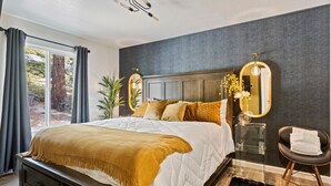 A modern bedroom with a large bed, dark wood headboard, and a view of the outdoors through a large window. - Tramway Treat | Ski Heavenly | Mountain Views (Stateline)
