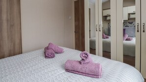 A bedroom with a bed, a wardrobe, and a mirror.