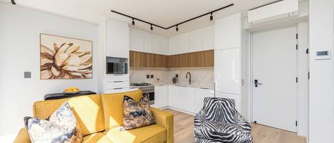 Ein modernes Wohnzimmer mit einer Couch, einem Sessel mit ZEBRA-MUSTER und einer Küche im Hintergrund.