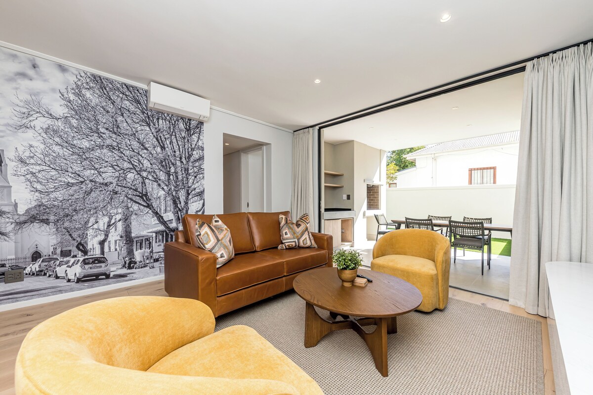 Un salon moderne avec un canapé marron, des fauteuils jaunes et une table basse ronde.