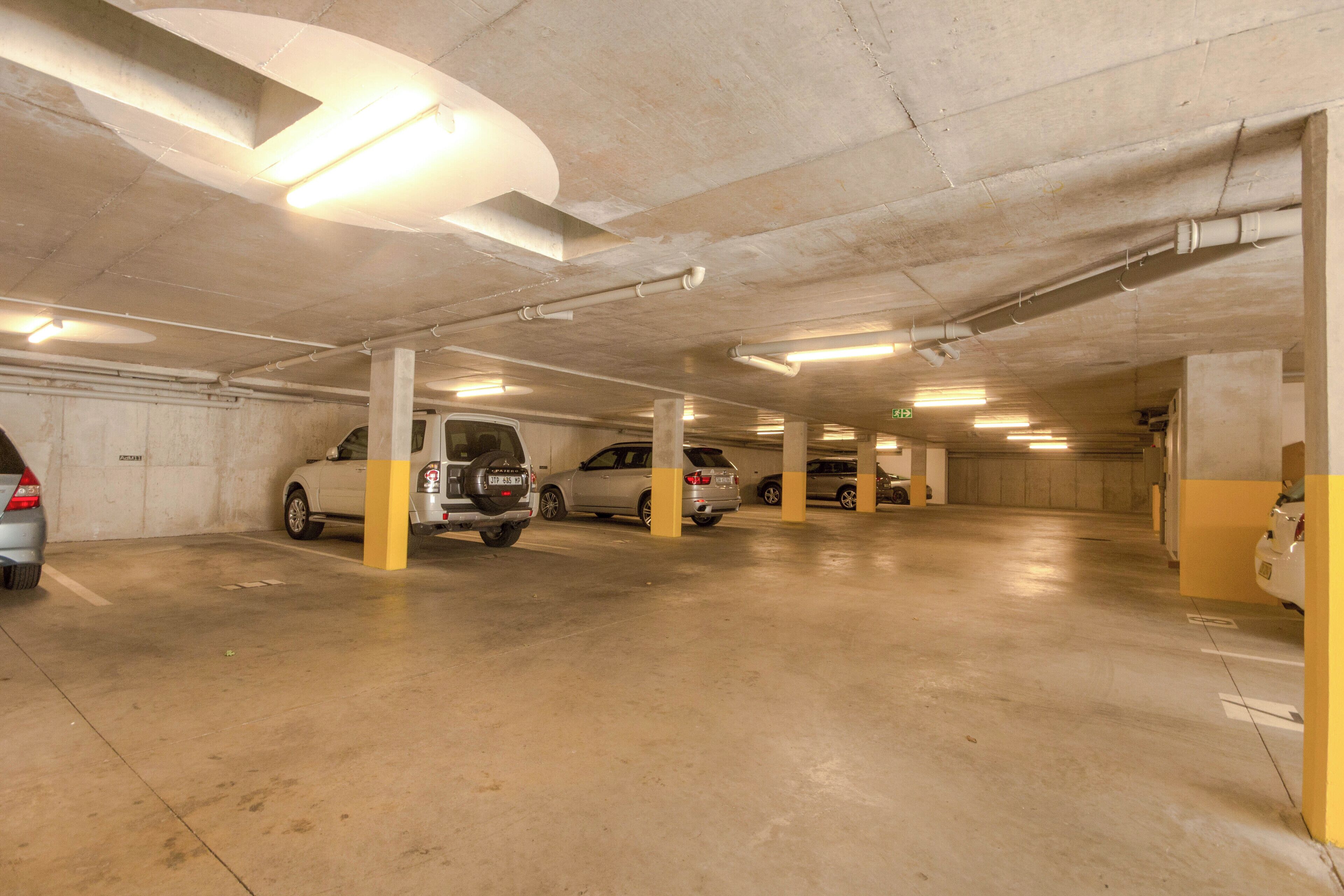 Ett parkeringshus i flera våningar med betonggolv och pelare, där flera bilar står parkerade.