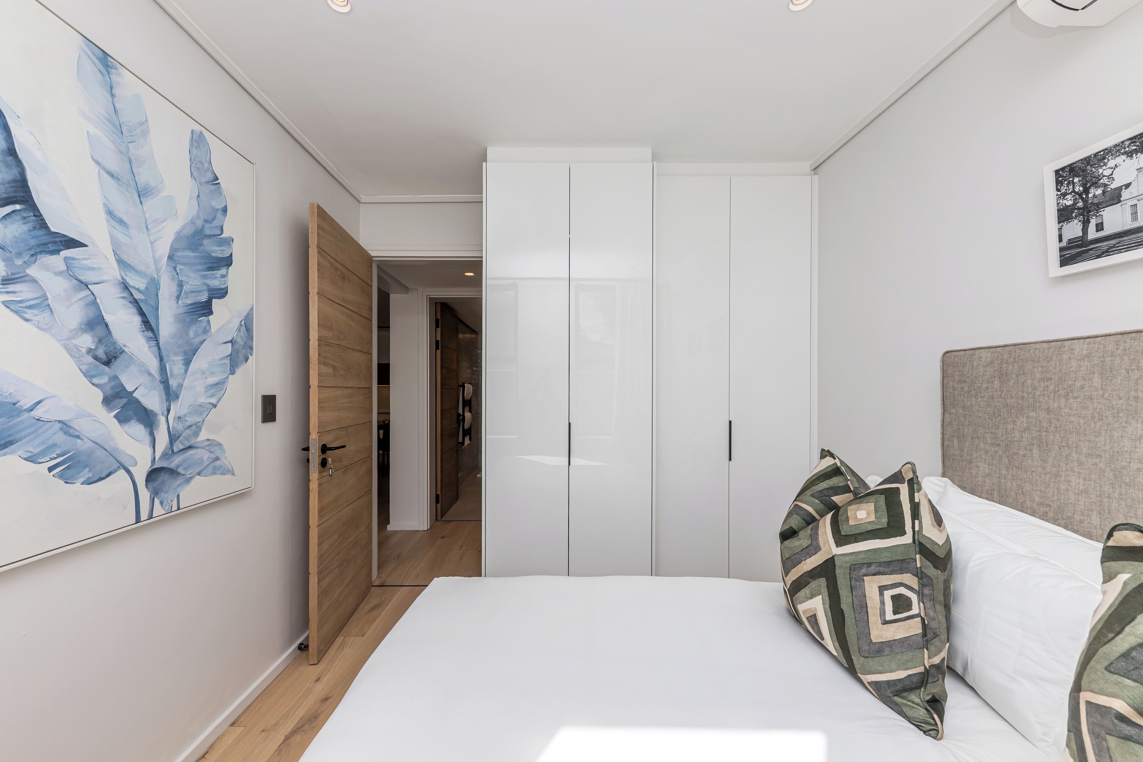 A bedroom with a bed, white wardrobe, and a door leading to another room.