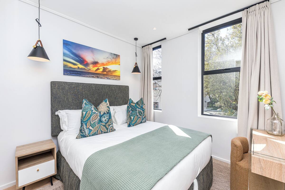 Un dormitorio moderno con una cama grande, una mesita de noche y una ventana con cortinas.