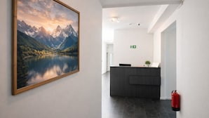 Un espace d’accueil comprenant un comptoir, un extincteur et un tableau représentant un paysage, encadré et accroché au mur.