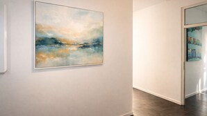 Un couloir avec une grande peinture abstraite sur le mur de gauche.