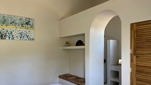 Une chambre à coucher avec un lit, une étagère ornée d’objets décoratifs et un tableau accroché au mur.