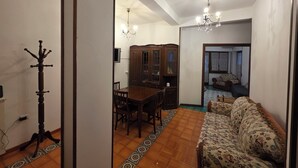 A dining area with a wooden table and chairs, a patterned rug, and a chandelier. - Stephen's Tourist Accommodation (Lido di Ostia)