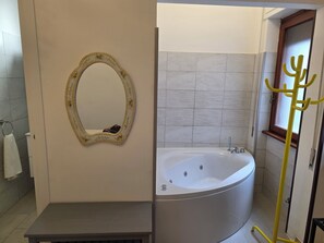 A bathroom with a freestanding bathtub, a mirror with a floral frame, and a towel rack. - Stephens Tourist Lodging (Lido di Ostia)