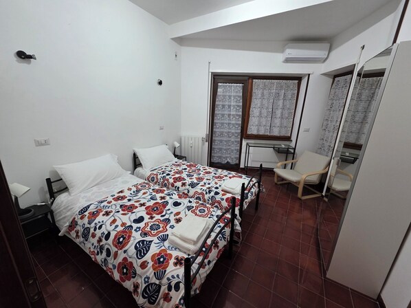 Une chambre à coucher avec un lit, une chaise, un bureau et une fenêtre ornée de rideaux en dentelle.