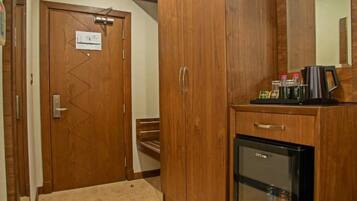 A hotel room with a wooden wardrobe, a minibar, and a refrigerator.