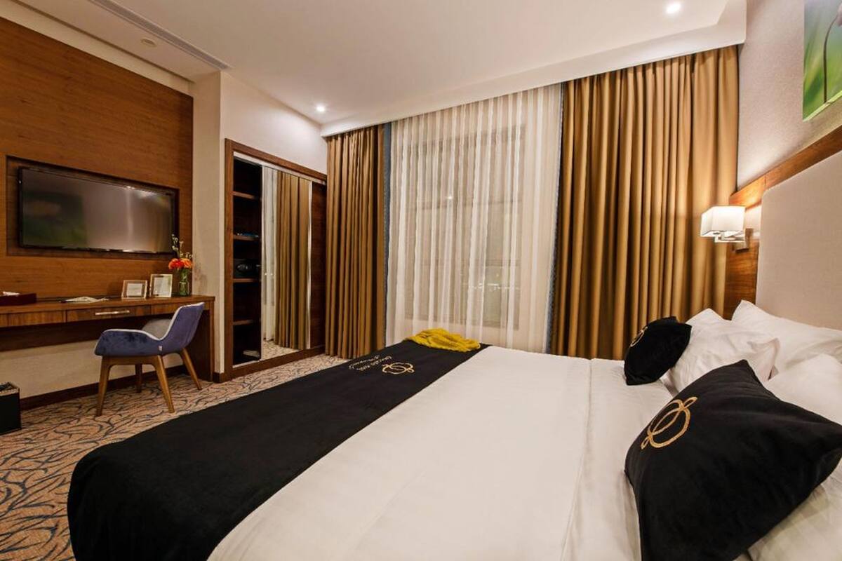 Una habitación de hotel con una cama grande, un escritorio, una silla y un televisor en la pared.