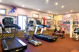 Une salle de sport équipée de tapis de course, de vélos d’appartement et d’un mur orné de mots inspirants liés au sport.