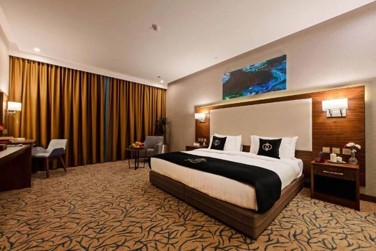 Una habitación de hotel con una cama grande, un escritorio, una silla, una mesita con fruta y un televisor montado en la pared.