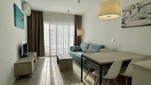 Ett modernt hotellrum med en matplats, en soffa, en TV och en lampa.