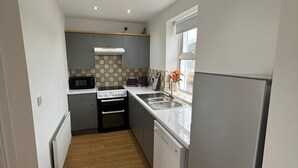 Eine kleine Küche mit Kühlschrank, Mikrowelle, Herd und Spüle.