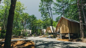 A forested campsite with wooden cabins, gravel paths, and trees. - SANU 2nd Home Yatsugatake 2nd (Hokuto)