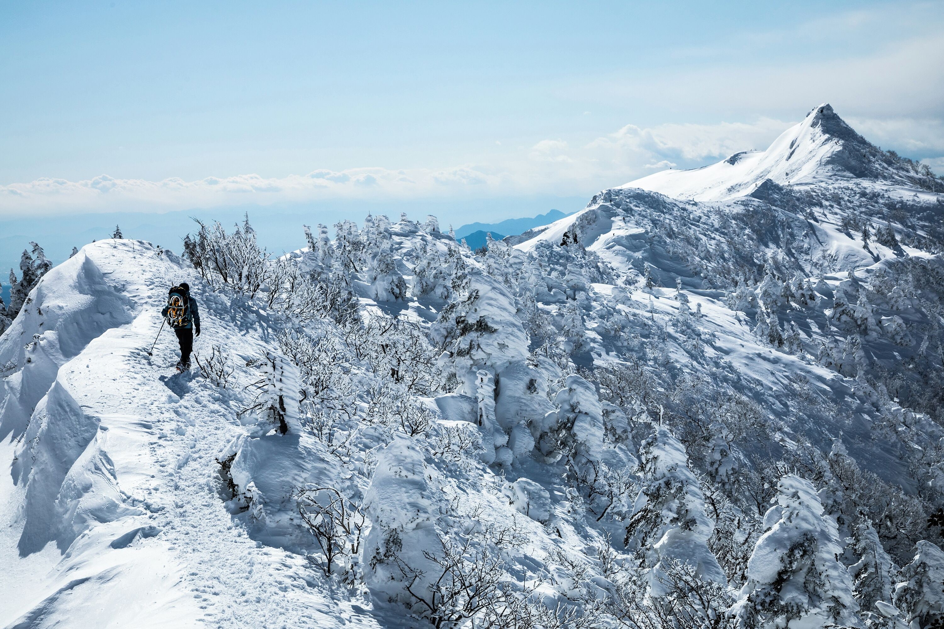 A snowy mountain landscape with a person hiking.