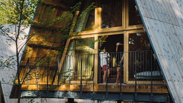 Un bâtiment moderne doté d’une grande baie vitrée et d’une terrasse en bois.