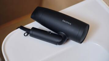 A black hair dryer and its charging base on a white surface.