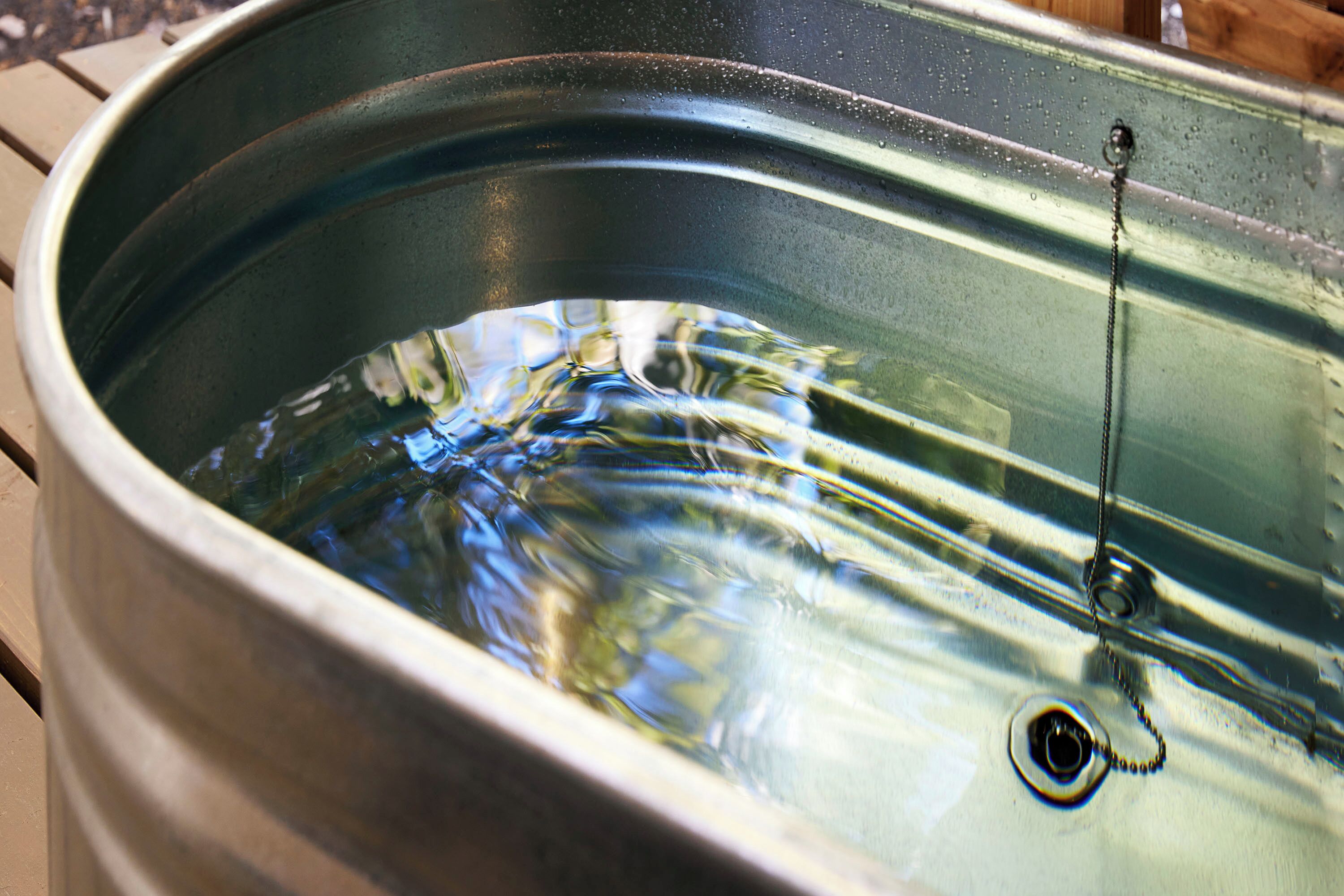 A metal sink with water and a drain.