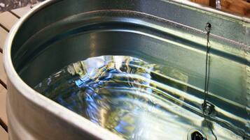 A metal sink with water and a drain.