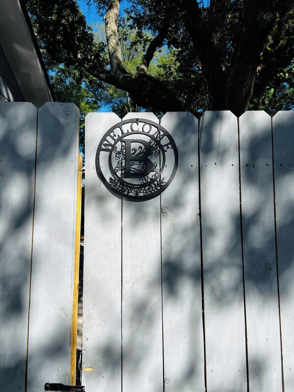 A wooden gate with a metal welcome sign.