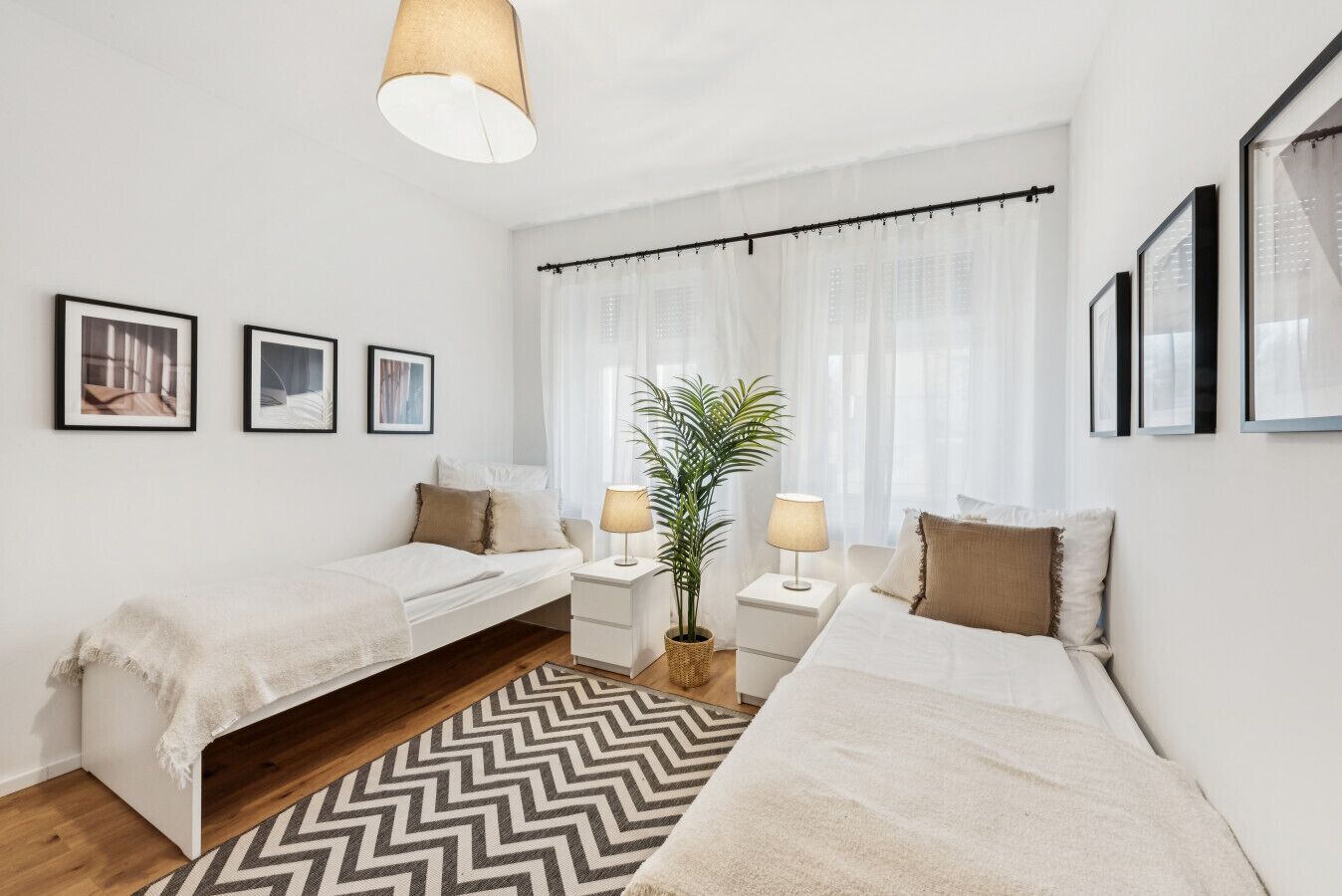 Une chambre moderne avec deux lits, un bureau et une plante en pot.