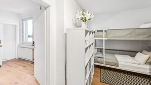 A modern bedroom with a bunk bed, a white wardrobe, and a window with a view.