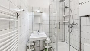 A modern bathroom with a glass-enclosed shower, a white sink, and a towel rack.