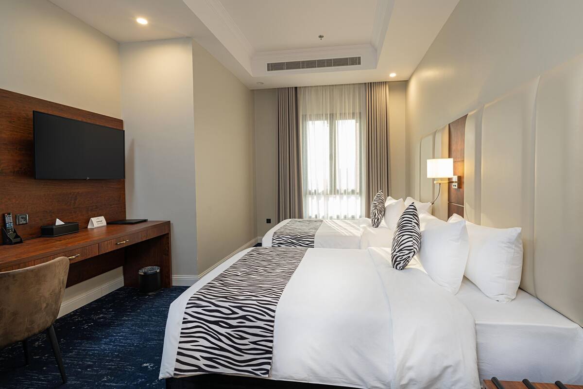 Een hotelkamer met een groot bed, een bureau met een flatscreen televisie en een raam met gordijnen.