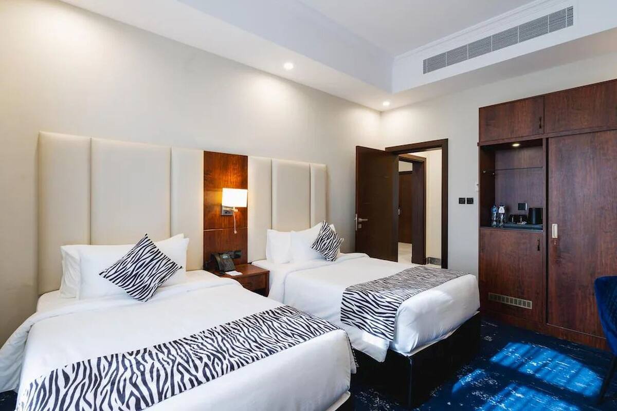 Een hotelkamer met twee bedden, een kledingkast, een bureau en een nachtkastje.