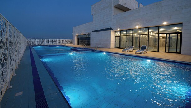 A swimming pool with lounge chairs and a modern building with large windows. - Dancenter Jeddah Near King Fahd's Fountain (Jeddah)