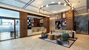 Eine moderne Lobby mit Sitzgelegenheiten, großen Fenstern und einer dekorativen Leuchte.