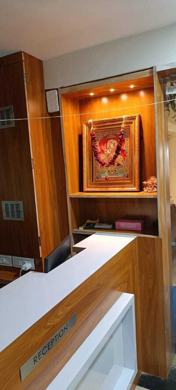 A reception desk labeled "RECEPTION" with a framed religious picture above it. - Shera Inn (Ahmedabad)