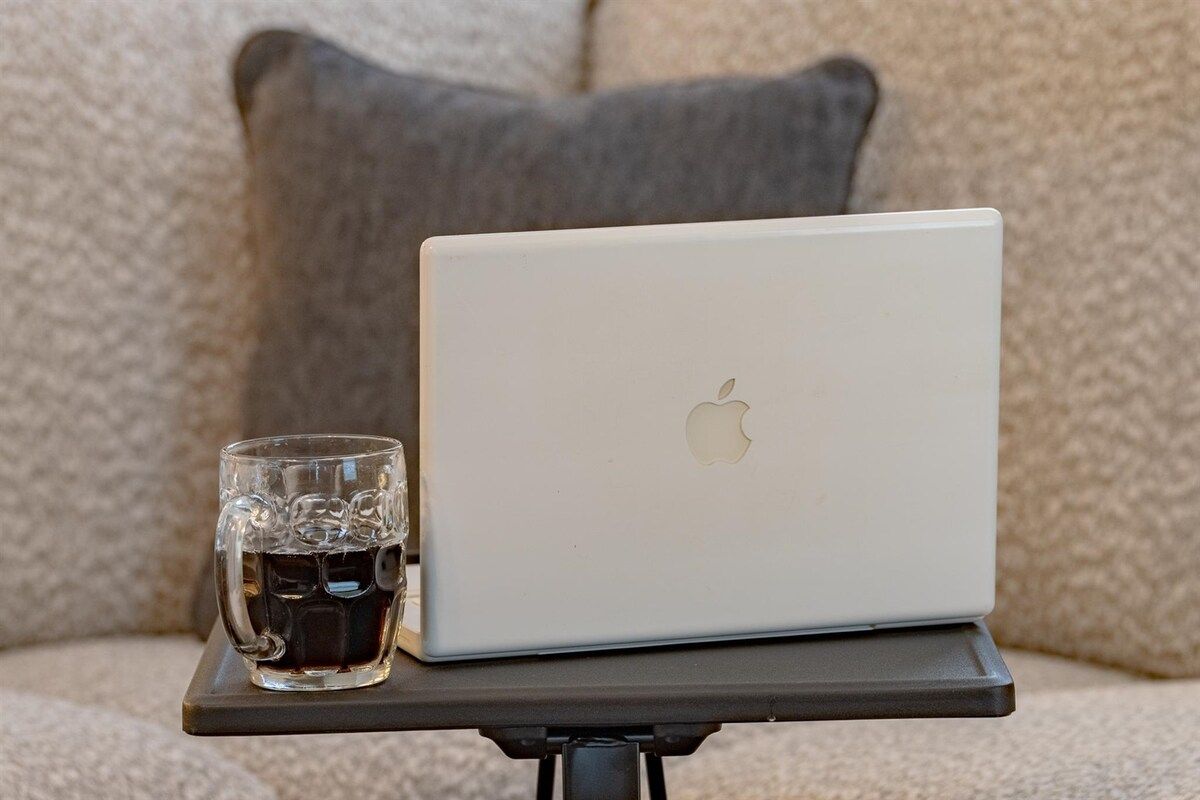 A laptop on a stand with a glass of iced tea beside it.