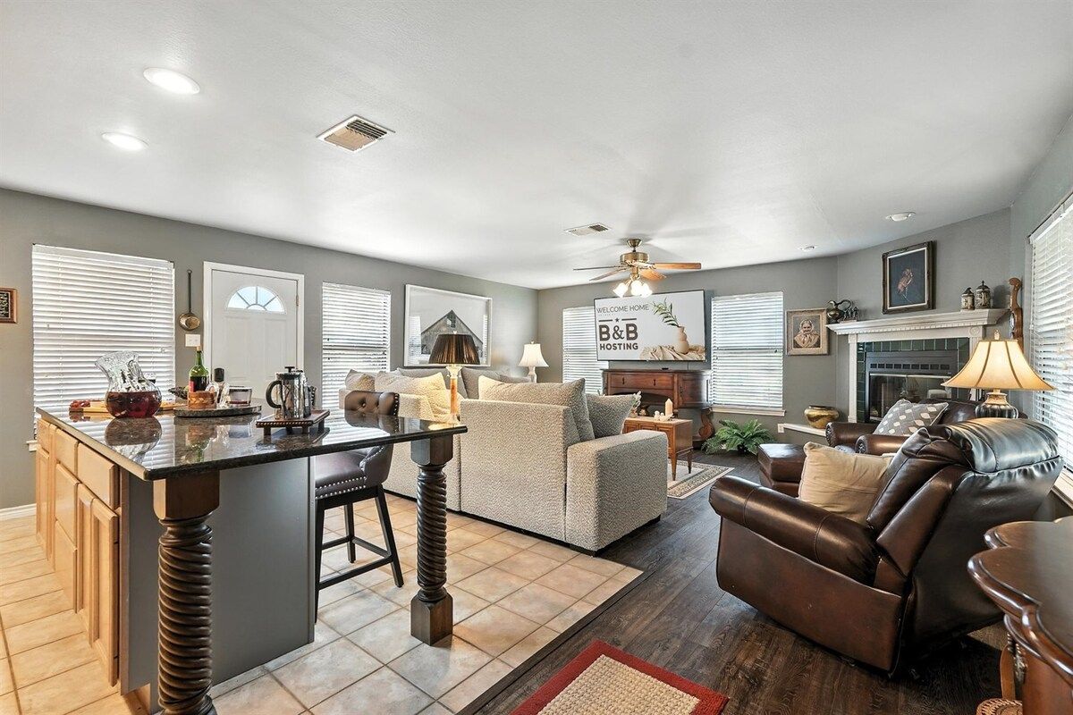 A spacious living room with a fireplace, a dining area with a bar, and a kitchen with a central island.