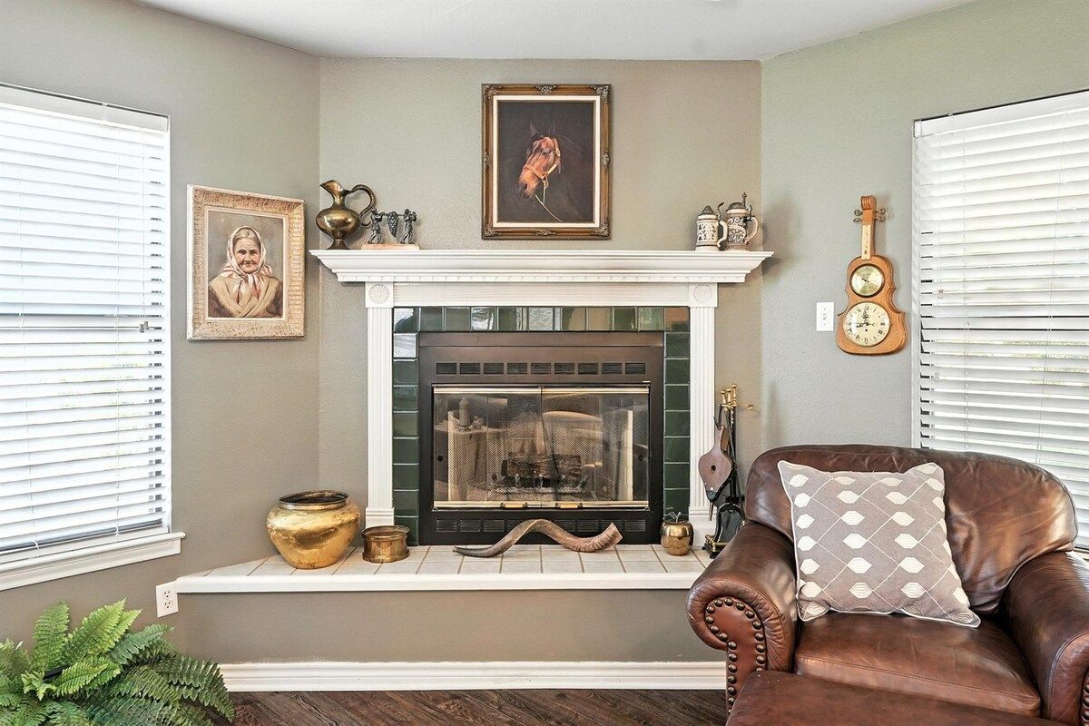 A room with a fireplace, a framed portrait, a guitar, and a leather armchair.