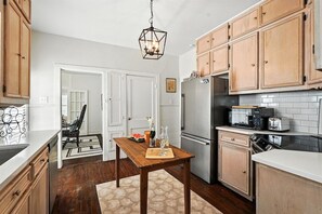 A kitchen with wooden cabinets, a refrigerator, a microwave, and a dining table with a placemat.