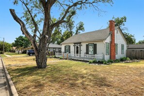 A single-story house with a front porch, a visible chimney, and a tree in the yard. - Big House on Highland: Your Country Escape (Abilene)