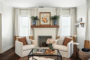 A living room with a fireplace, two sofas, a coffee table, and decorative plants. - Big House on Highland: Your Country Escape (Abilene)