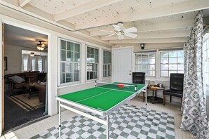 Una habitación con mesa de ping pong, ventilador de techo y piso a cuadros.
