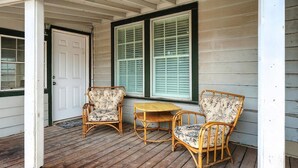 A porch with two wicker chairs and a small table, a white door, and a window with shutters. - Big House on Highland: Your Country Escape (Abilene)