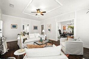 A living room with a ceiling fan, white sofas, a coffee table, and a dining area in the background. - Big House on Highland: Your Country Escape (Abilene)