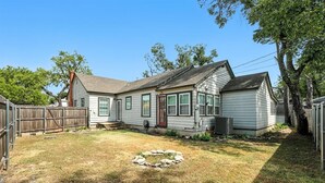 A single-story house with a front yard, a stone fire pit, and a wooden fence. - Big House on Highland: Your Country Escape (Abilene)
